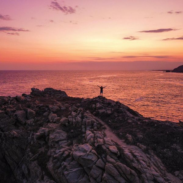 Silhouette of a person meditating against a vibrant sunrise.
